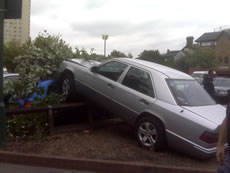 car on fence outside Morrisons, Acton
